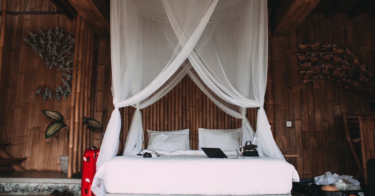 Laptop in checked baggage - Cozy hotel bed with laptop under canopy