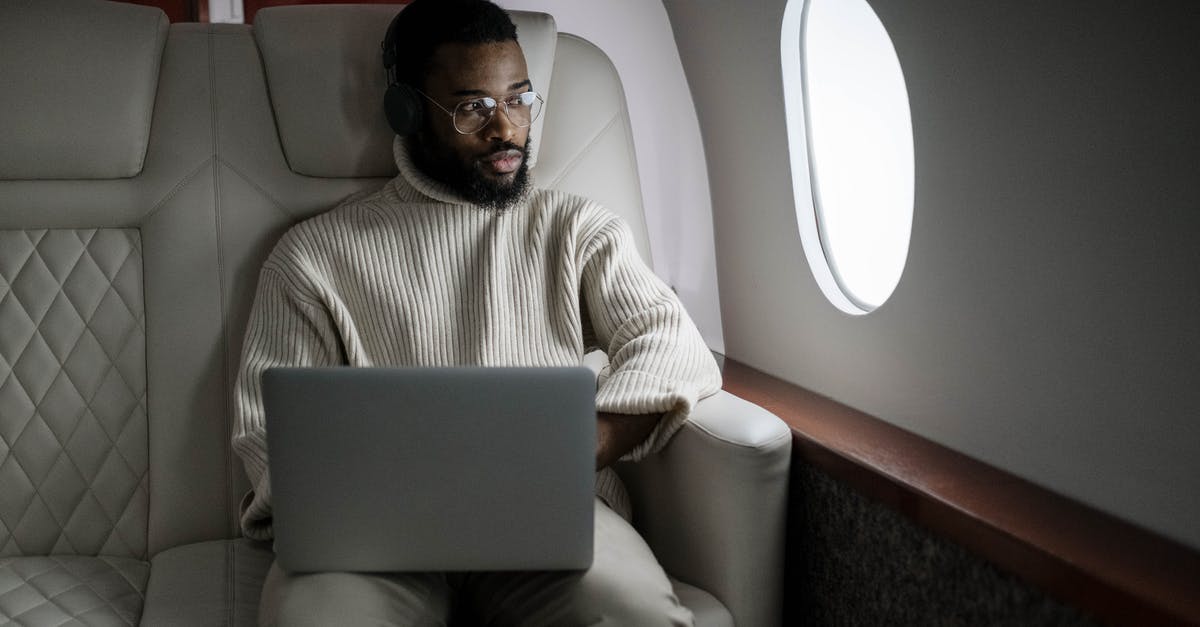Laptop left on Emirates flight - Man in White Sweater Sitting on Couch Using Macbook