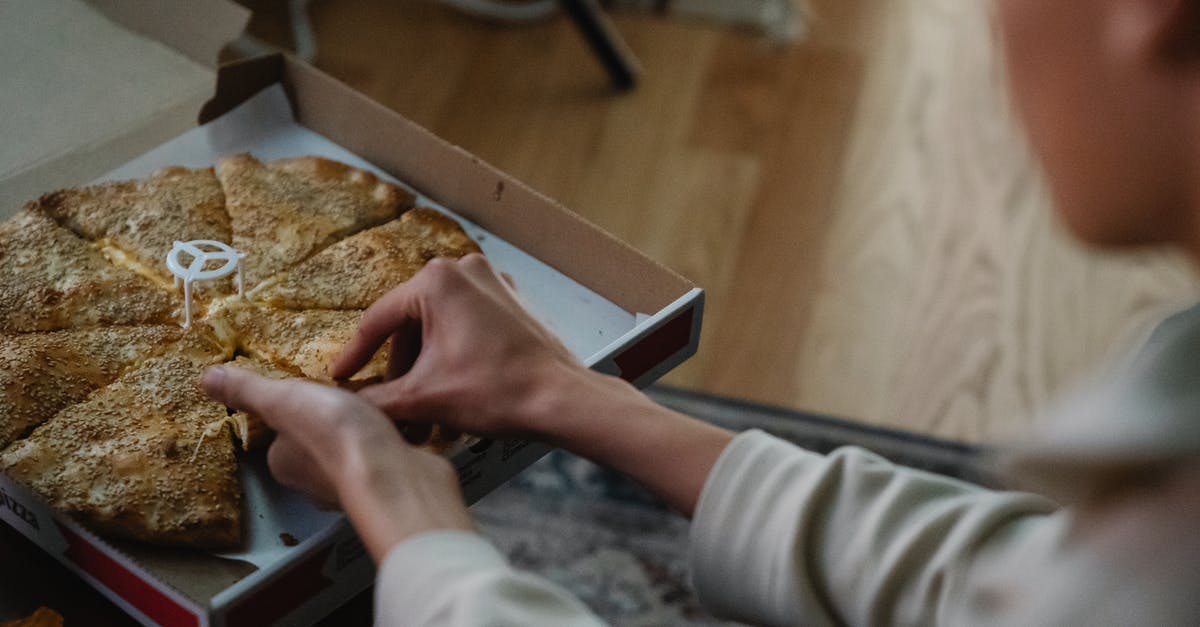 Late night buses from Helsinki airport to Turku in December? - From above crop anonymous person taking slice of delicious pizza from carton box on table spending evening at home