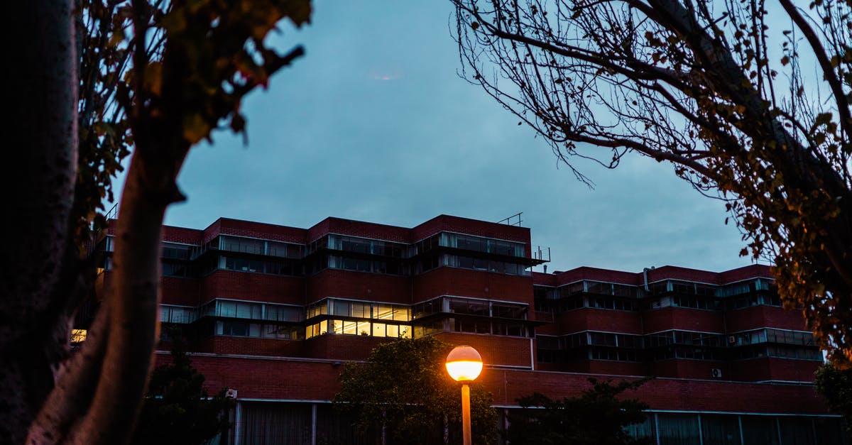 Late night buses from Helsinki airport to Turku in December? - Low angle view from silhouettes of trees on multistory building and luminous lamp in dark evening