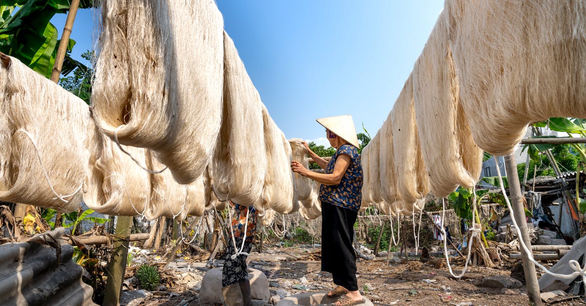 Layover in Addis Ababa: need to collect checked luggage? - Aged Asian person drying spun fibers of silk in sun