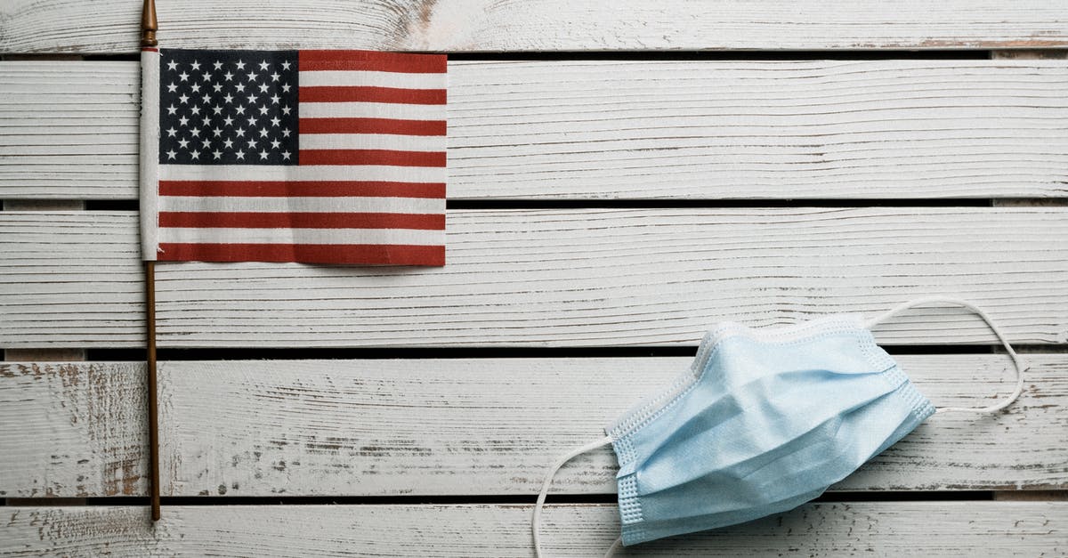 Layover in CDG, traveling from India to US during COVID - American Flag and disposable mask on wooden table