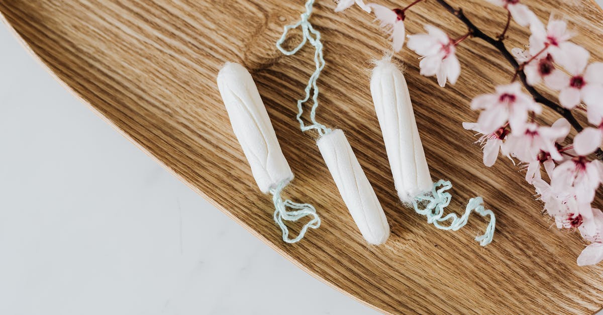 Leave to stay for 6 months cooling period - From above of hygienic cotton tampons placed on bamboo board with small pink flowers