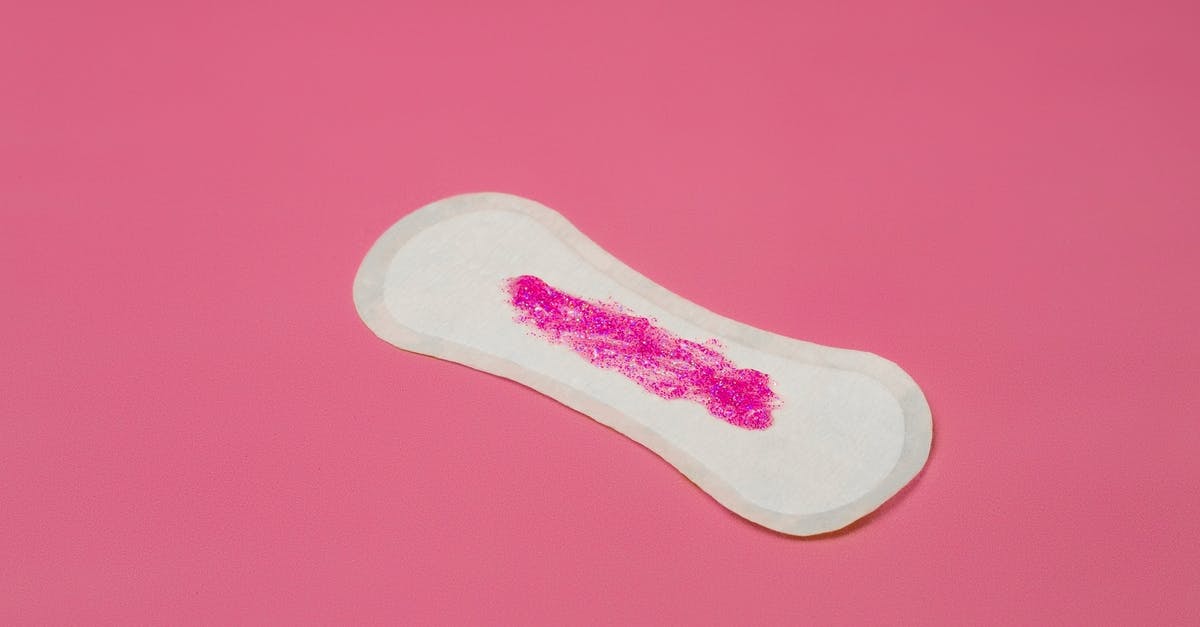 Leave to stay for 6 months cooling period - From above of feminine white hygiene pad with pink paints as symbol of menstruation placed in studio