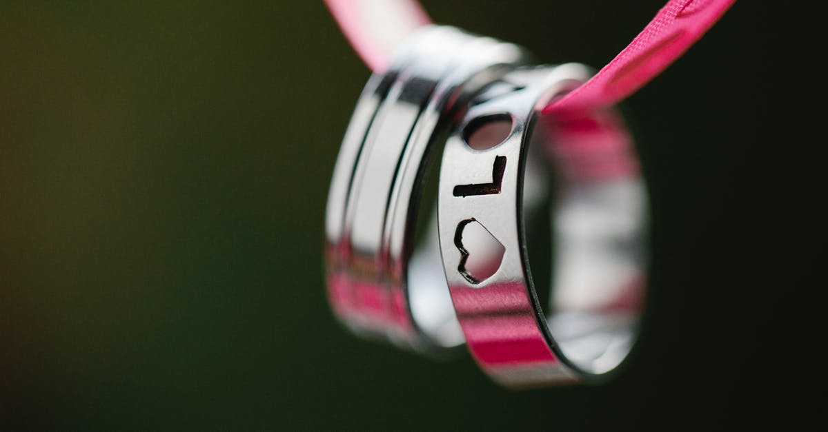 Leaving Mexico after 90 days as part of ESTA requirements - Soft focus macro of silver rings with engraved Love inscription and heart hanging on pink ribbon during romantic holiday celebration