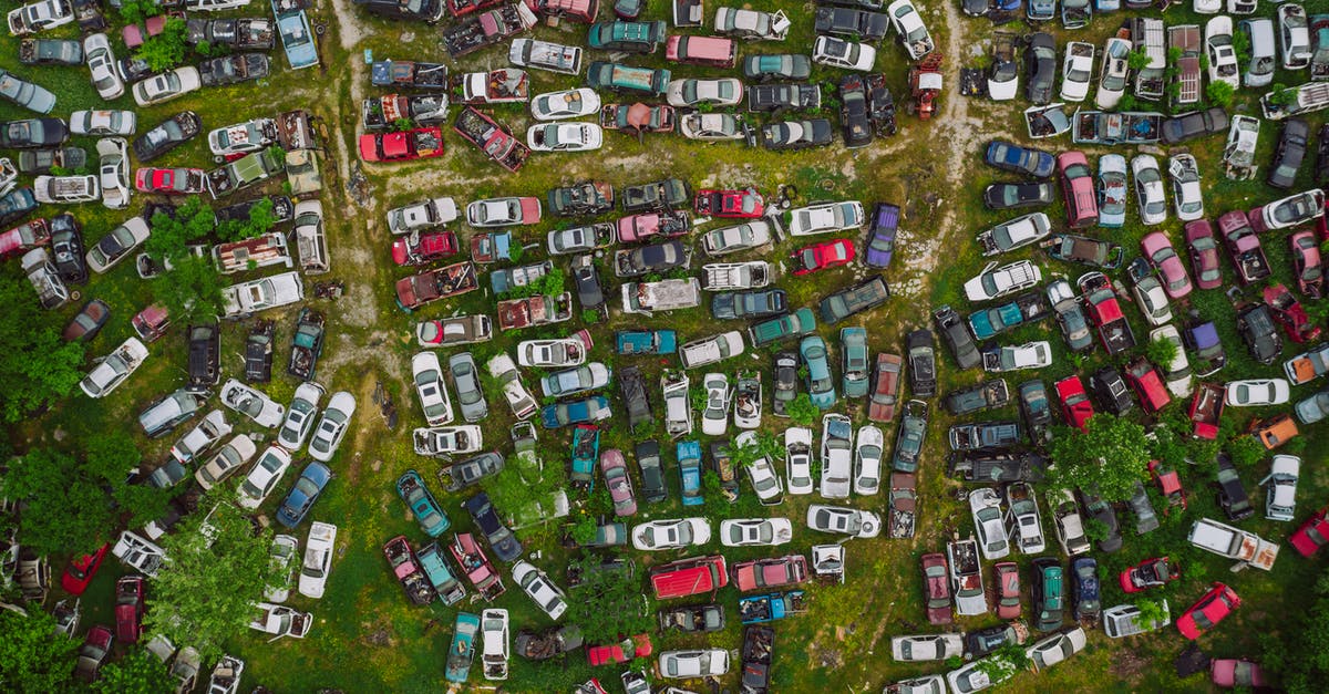 Leaving Sweden with a different passport? - Drone top view of old desolated vehicles of different colors in automobiles graveyard