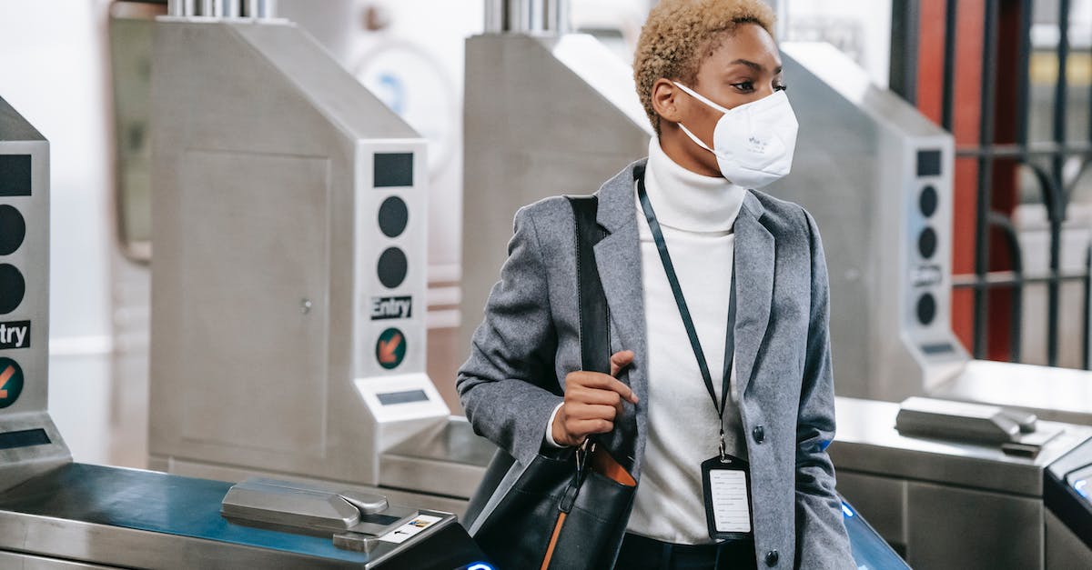 Legalities and safety concerns of visiting prostitutes in Amsterdam - Calm attractive African American female in stylish formal wear and protective mask passing through turnstile gates in underground station