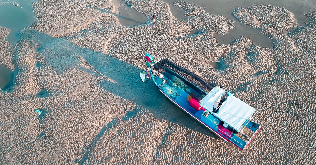 Location in ocean furthest from any land. Are there any established organized travel options for a tourist? - From above of large boat moored on sandy beach with people exploring coast in sunny day
