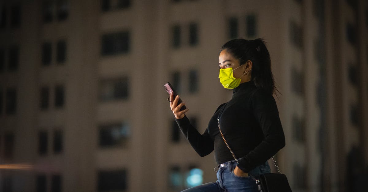London night bus safety - Woman in a Mask Using Phone on a Street at Night