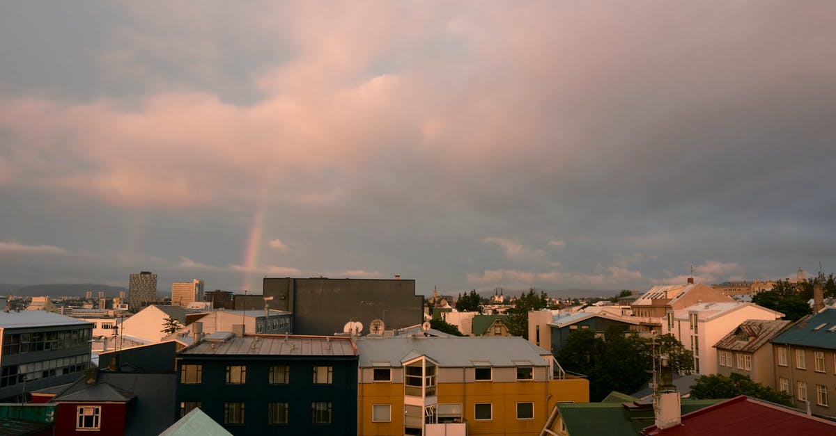 Long Layover (20h) in Reykjavik (Iceland), visit city? - Small town under cloudy sky and rainbow