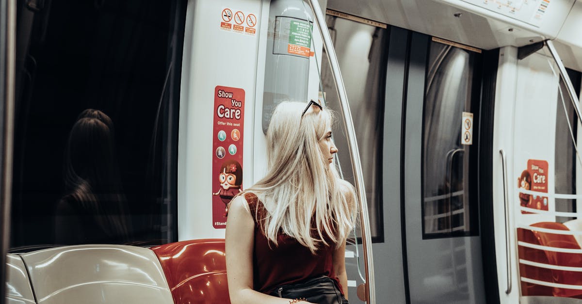 Long Transit in Cairo [duplicate] - Young female passenger with long blond hair in stylish outfit sitting on seat and looking away while commuting by modern train