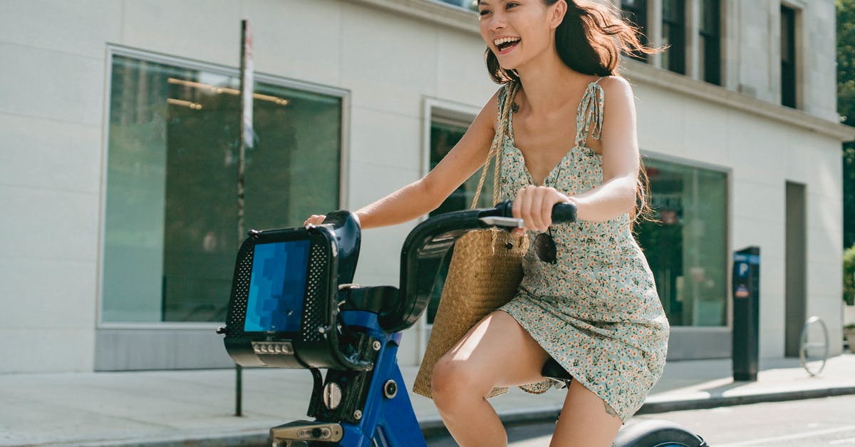 Long-distance Uber/Lyft ride around Christmas - Happy young Asian lady smiling and riding bike on street