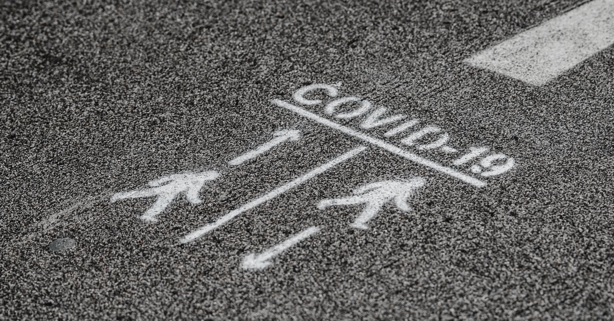 Longest distance ordinary road sign? - From above COVID 19 warning inscription about social distance on asphalt pavement on street