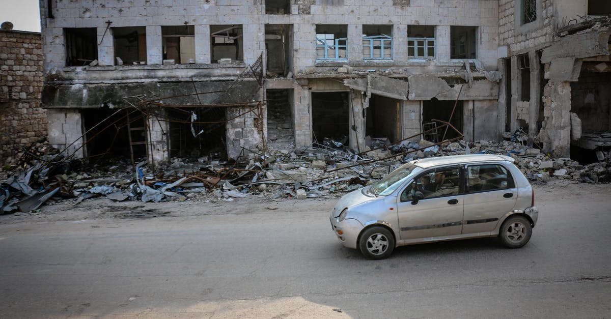 Longest uninhabited road segments - Automobile parked on road near old demolished house with broken windows and remains of building in poor district of town