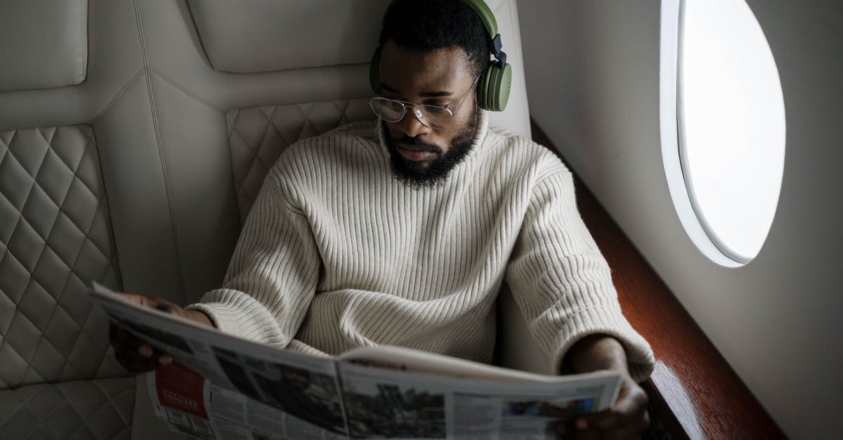 Long-haul flight with baby - parents spread across the plane - Man Reading a Newspaper