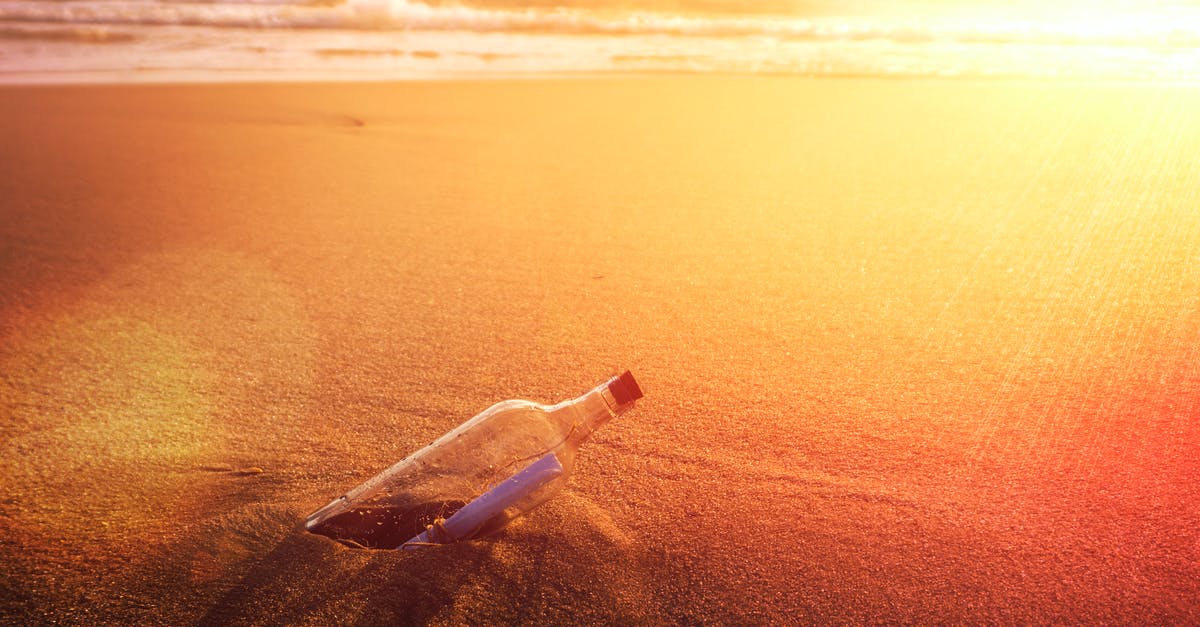 Lost and found on Cycladic islands - Clear Glass Bottle on Brown Sand