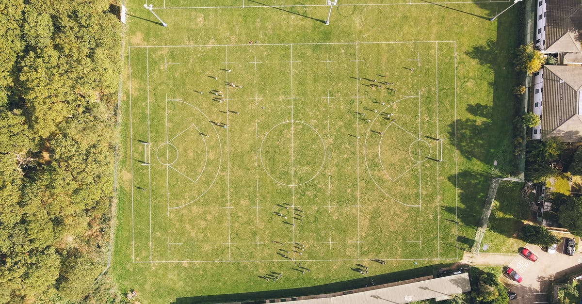 Lost property on Portuguese trains - Drone view of rugby pitch surrounded by lush green trees near old residential houses on sunny day in countryside