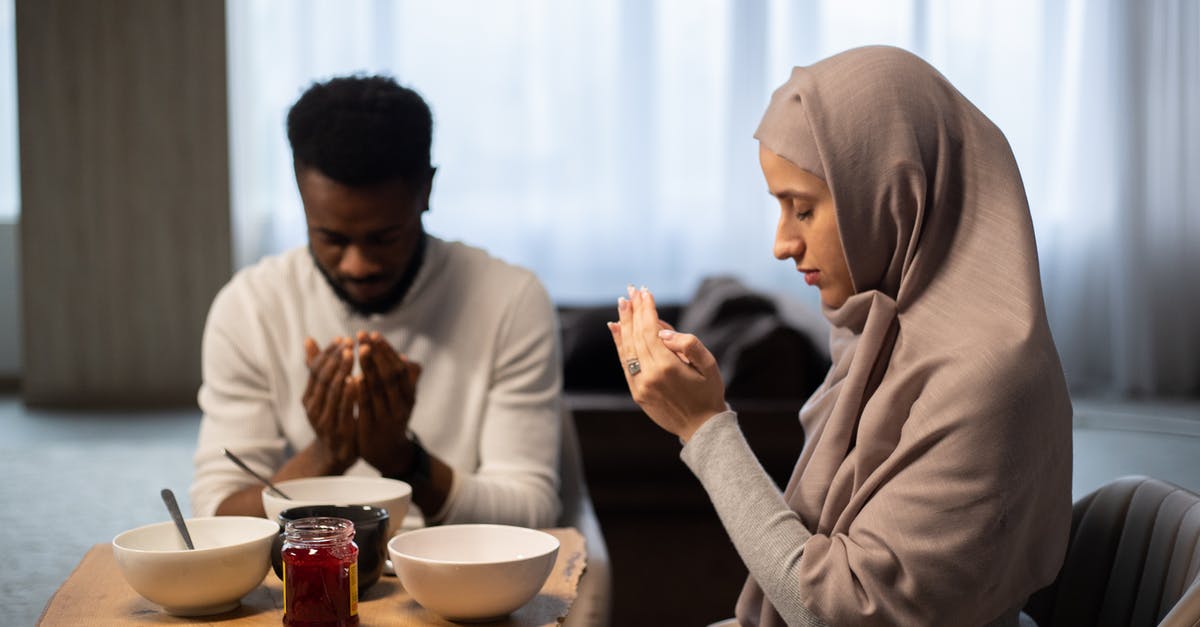 Lots of Muslim headscarfs on a Sunday in Hong Kong - Multiethnic couple praying at table before eating