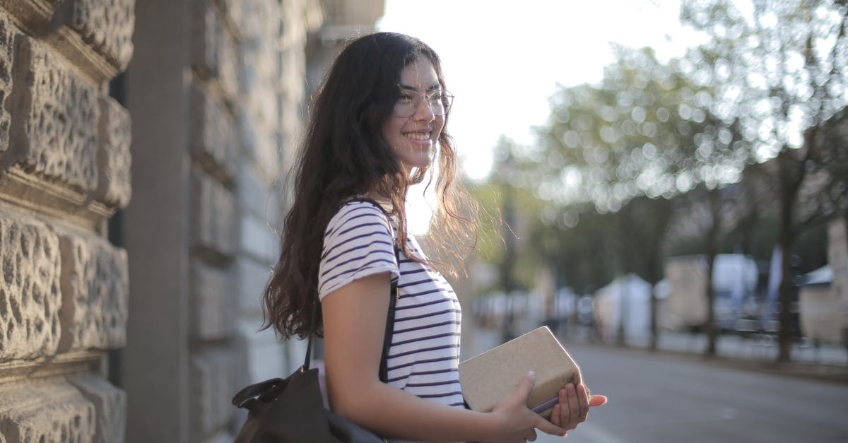 luggage allowance on multi-city bookings - Optimistic ethnic woman with stack of books in city