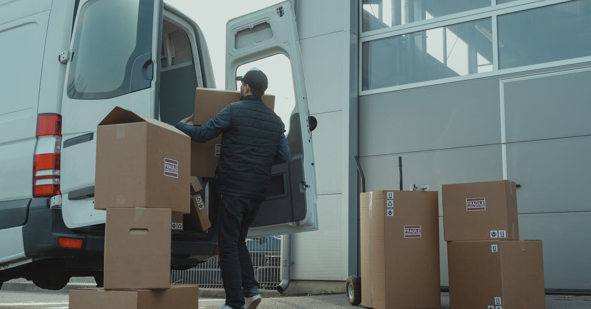 Luggage storage in Boston - Man in Blue Jacket and Blue Denim Jeans Sitting on Brown Cardboard Box