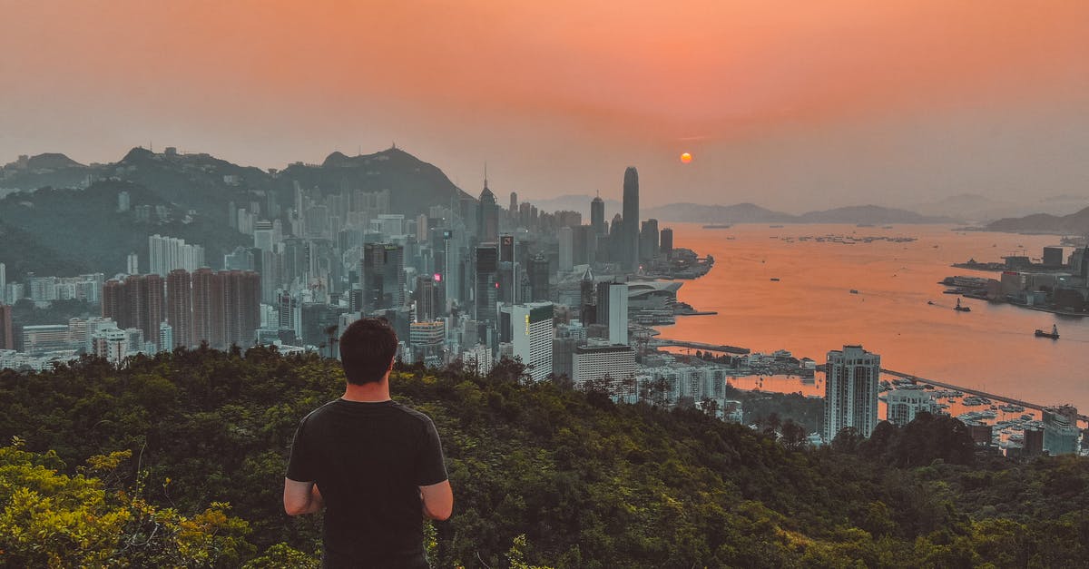 Macau/Hong Kong: Visa for going back and forth - Anonymous male hiker enjoying sunset over modern coastal city from viewpoint