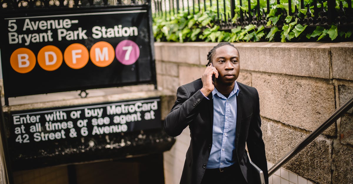 Manhattan subway for the claustrophobic - Well dressed African American businessman talking on cellphone while exiting New York subway on summer day