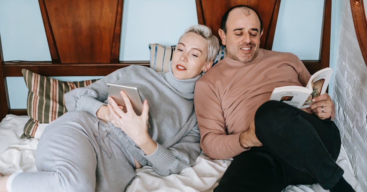 Married name on easyjet booking - Happy middle aged multiethnic couple cuddling while lying on comfortable bed together with book and tablet during lazy weekend at home