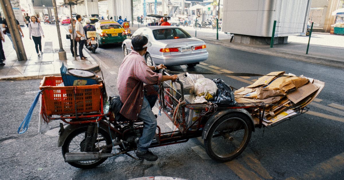 May a cyclist or a pedestrian cross from Switzerland to France near the Basel EuroAirport without going into the airport? - Full body side view of ethnic man carrying packages and cartons on tricycle while crossing asphalt road