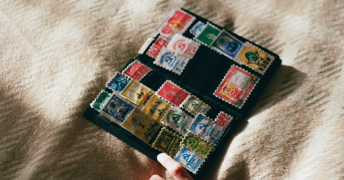 Meaning of various fields on a Schengen visa stamp - From above of crop unrecognizable person with collection of vintage stamps with illustrations on woolen textile