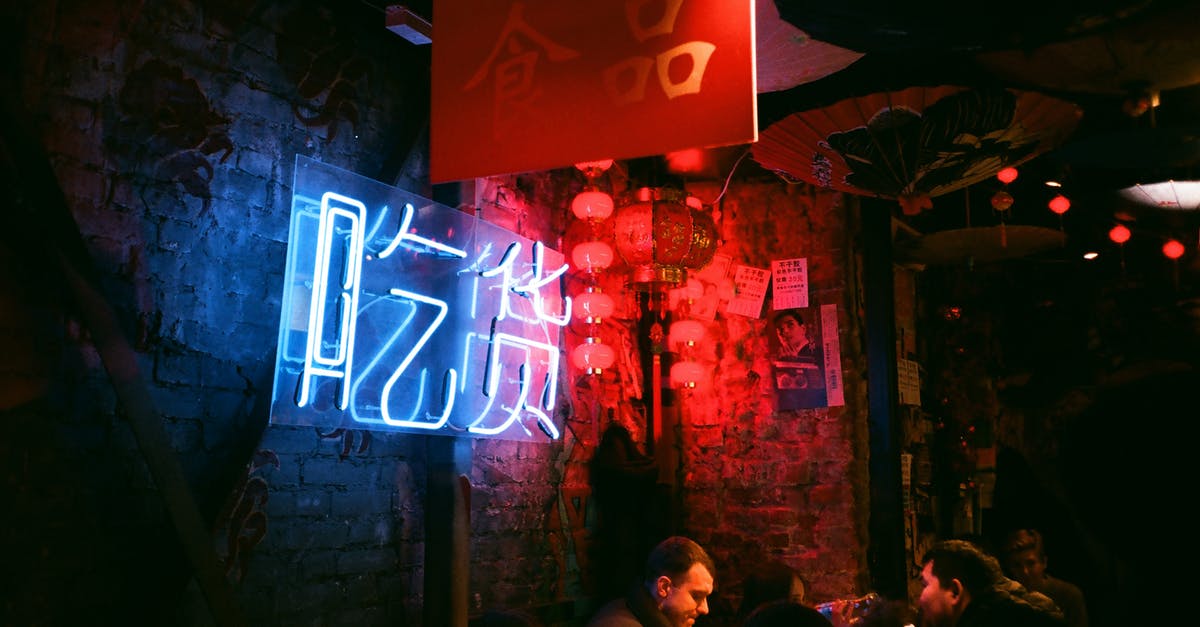 Meet locals in Edinburgh - Interior of crowded creative bar with shabby brick walls neon inscription and local Asian decorations