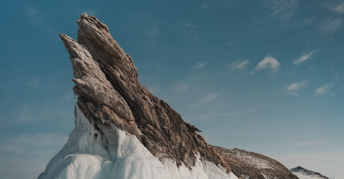 Mexican visa by land versus air - Rock with ice under cloudy sky in wintertime