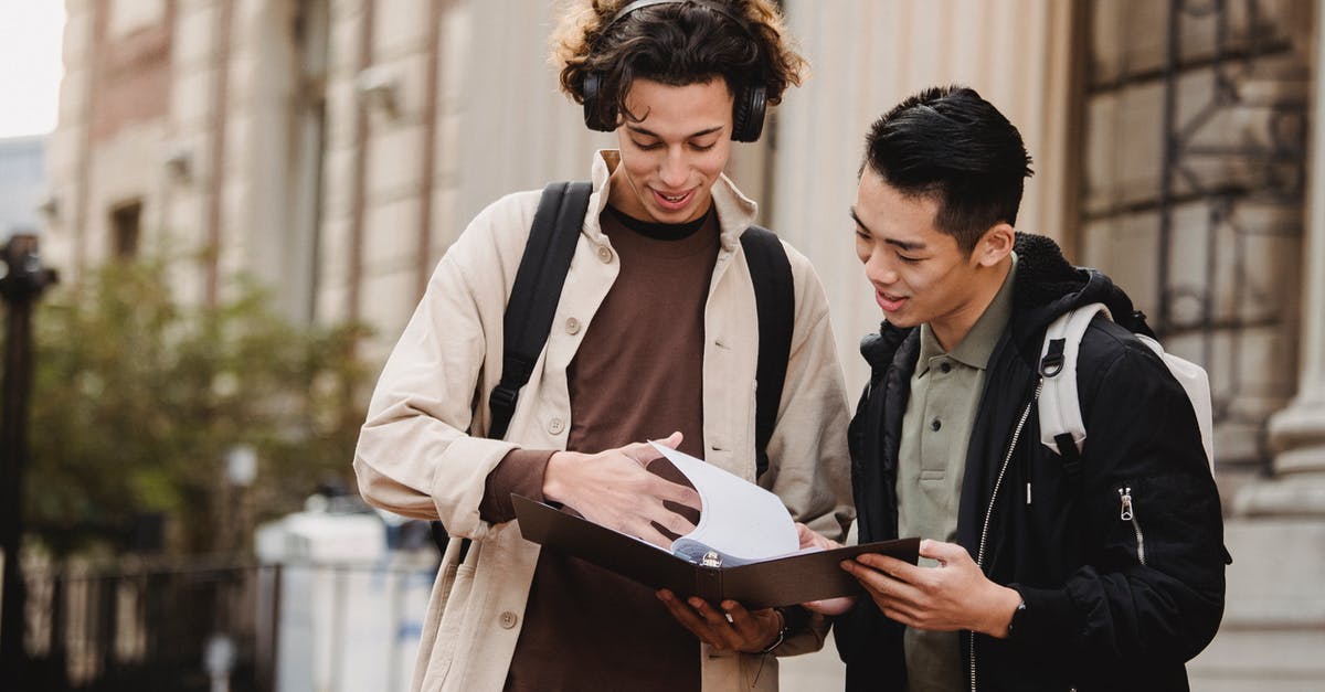 Minimum information required to file a fare in a GDS - Smiling multiracial classmates turning pages of file on folder with homework task near university