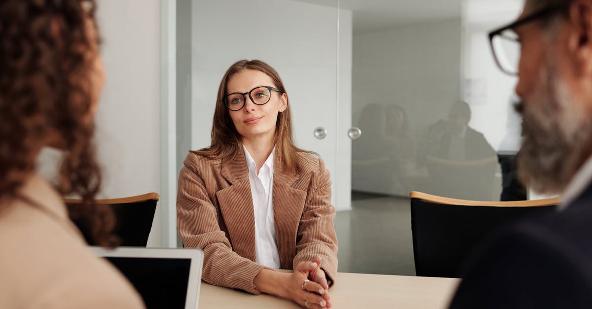 Minimum length of employment - Woman in Brown Blazer seated beside Table