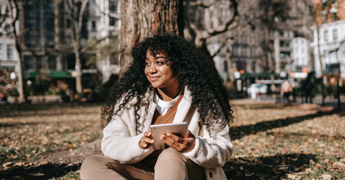 Missed ground connection - Black woman with tablet sitting on ground in city park