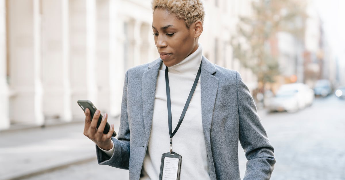 Mobile connectivity in Israel, in and outside small and large cities? - Confident young  African American lady with badge around neck standing on pavement and watching video on smartphone in daylight