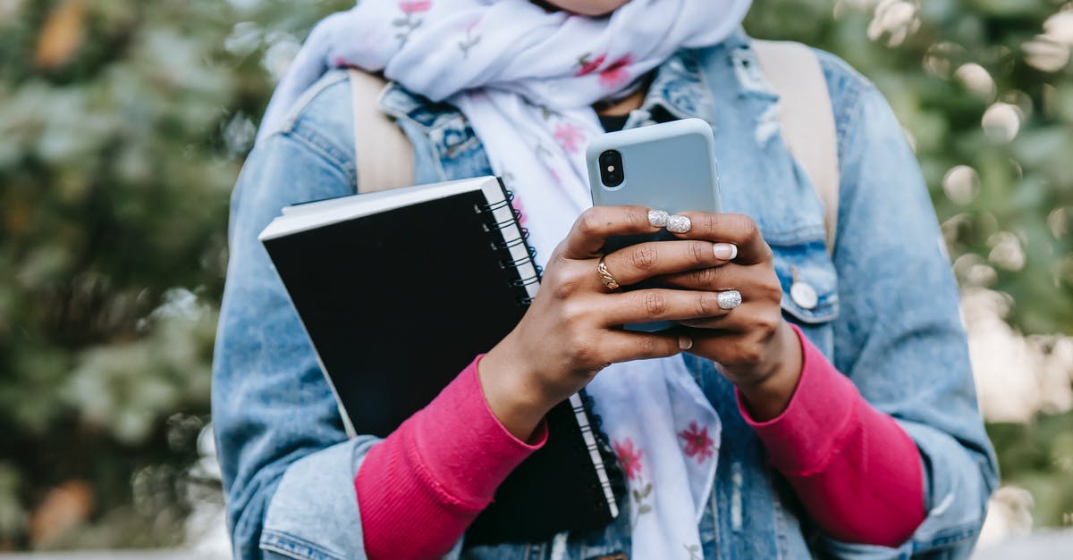 Mobile Internet Carriers in Eastern Europe [closed] - Crop anonymous female in headscarf and jeans jacket with rolled up sleeves and with notebook messaging on cellphone