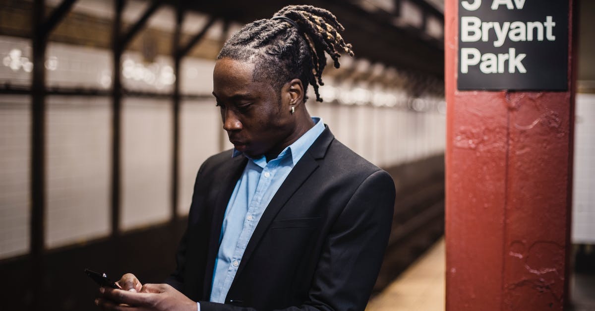 Mobile internet in New York City - Serious young man using smartphone while waiting for metro train