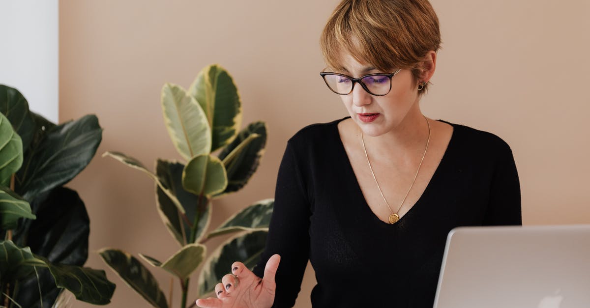 Mobile phone connection in Macedonia for short visit - Concentrated female manager in casual outfit and eyeglasses reading message on smartphone while sitting at table with laptop in cozy workspace