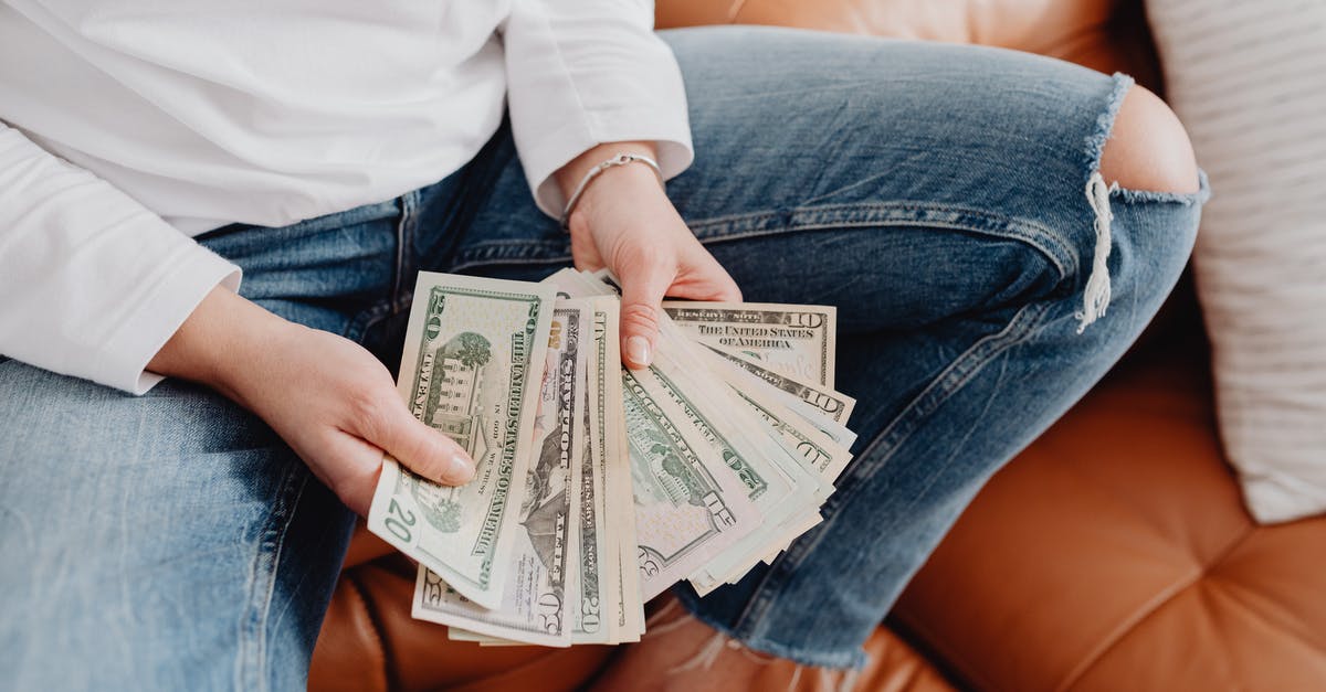 Money limit in the airport - Low Section of a Woman Sitting on a Leather Sofa and Showing Dollar Banknotes