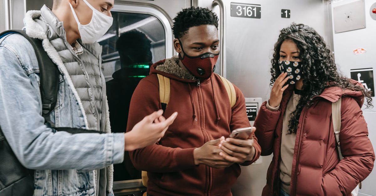 Moscow subway last train time - Faceless multiethnic students in masks in subway train with phone