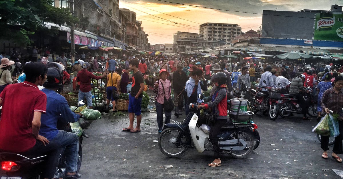 Motorcycle insurance in Southeast Asia - Woman in Gray and Red Jacket Riding White Motor in Crowded Place