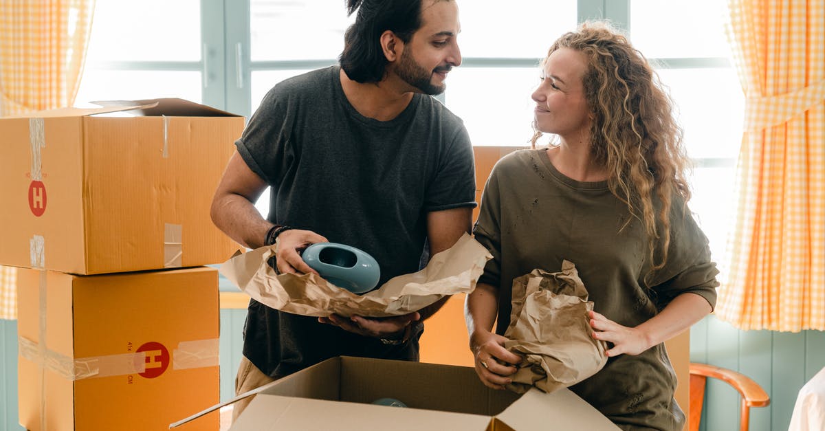 Moving from one SkyTeam partner to another - Multiethnic couple packing ceramic belongings in parchment before relocation