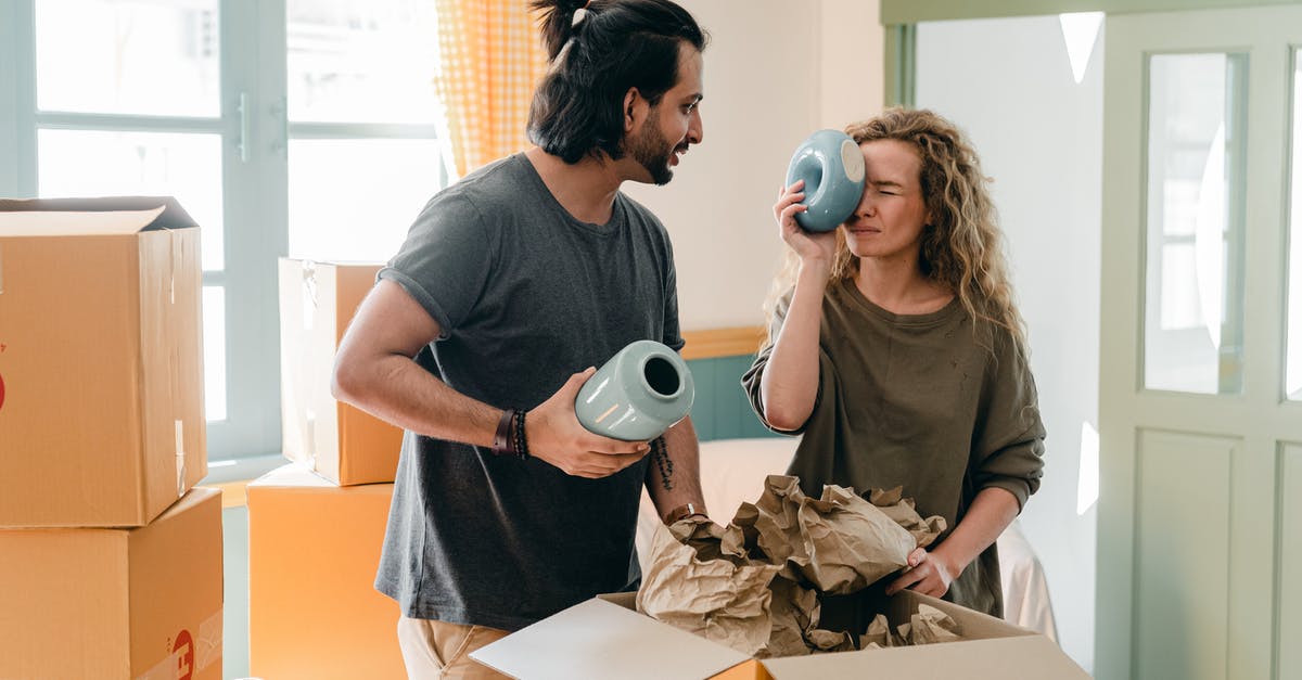 Moving from one SkyTeam partner to another - Multiethnic couple with ceramic vases and pile of cardboard boxes