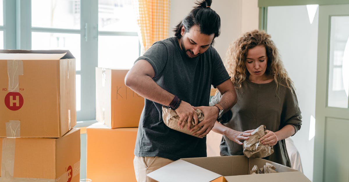 Moving from one SkyTeam partner to another - Diverse couple packing belongings in parchment near different boxes indoors