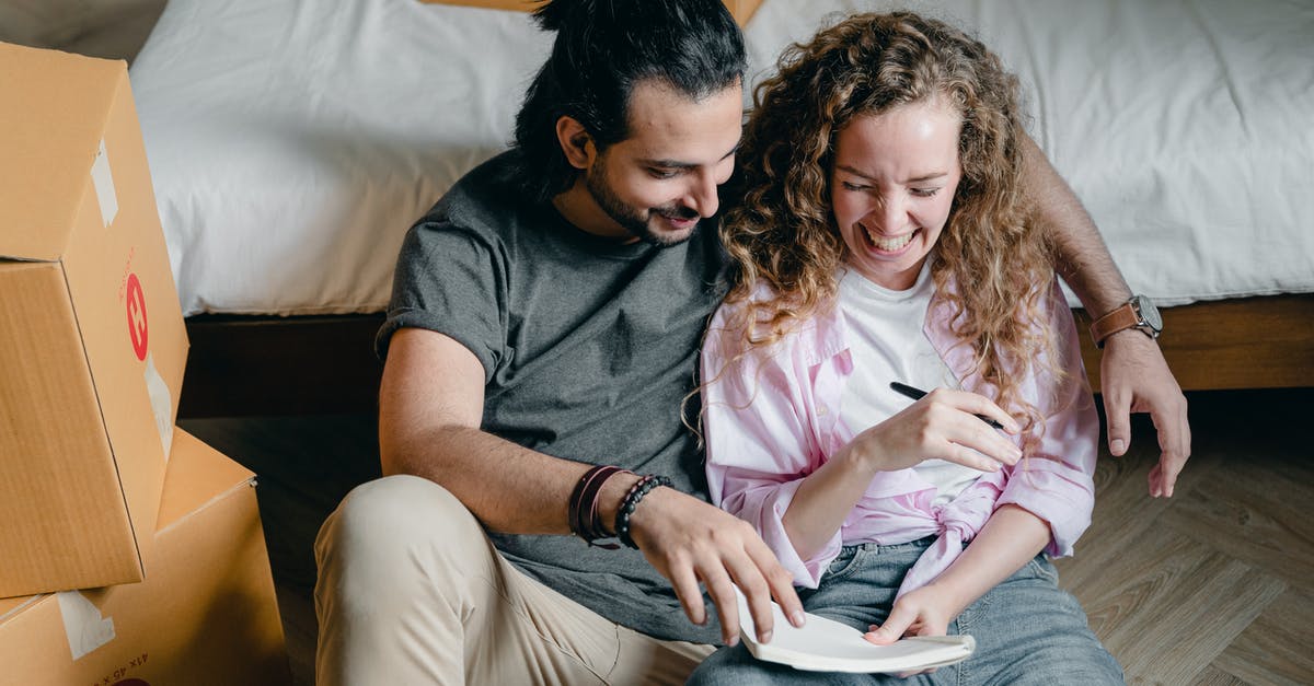 Moving Germany from Belgium [closed] - Cheerful couple with notebook moving house