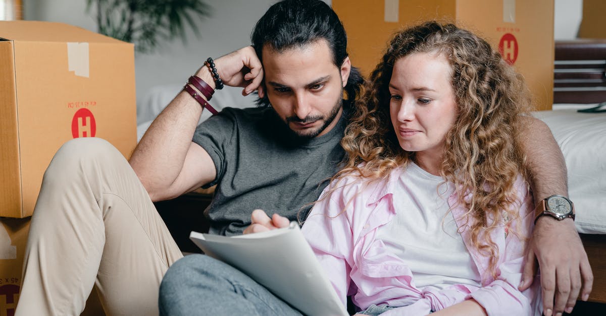 Moving inside Ohrid, Macedonia [closed] - Pensive male and female in casual clothes sitting together among boxes and writing notes in notebook while leaning on bed