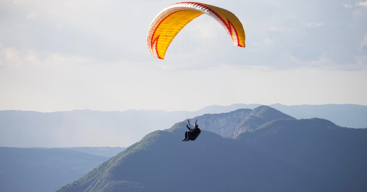 Multiple flight changes - any risk? - Anonymous paraglider flying over mountains in nature