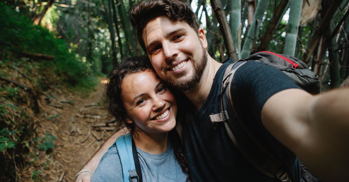 My girlfriend was refused a tourist visa - Happy couple of travelers taking selfie in forest