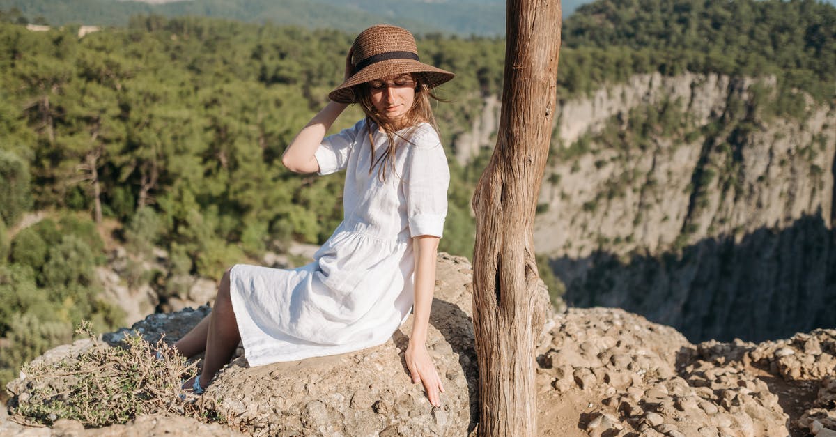 Nauseous Anxiety Travel - A Woman in White Dress Sitting on the Edge of a Mountain