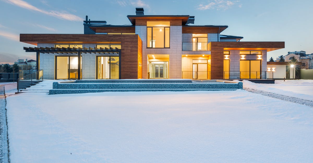 New passport and entrance Schengen - Exterior architecture of private suburban cottage house with stone and wooden facade and large windows overlooking spacious snow covered yard in winter day